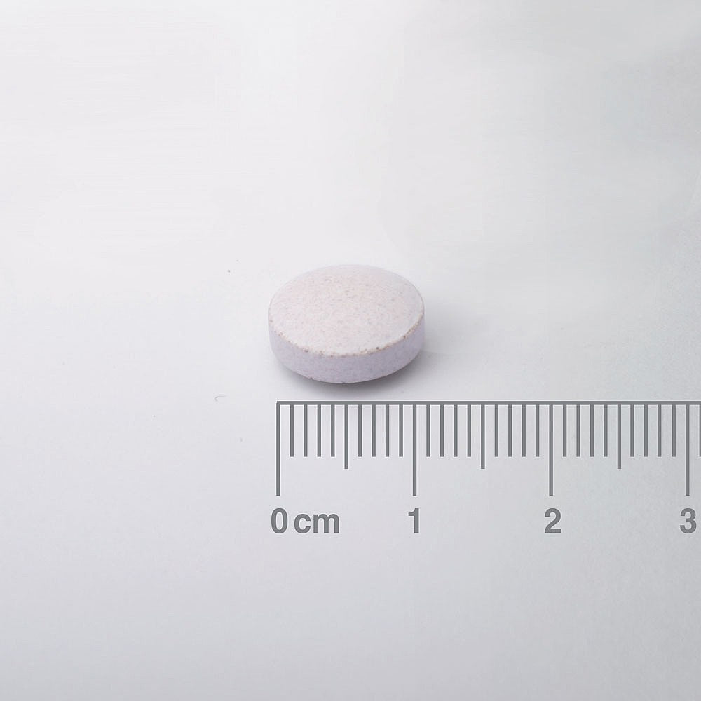 White pill with a ruler for scale on a white background