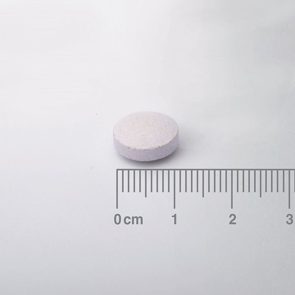 White pill with a ruler for scale on a white background