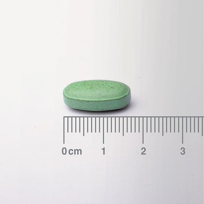 Green pill with a ruler for scale on a white background