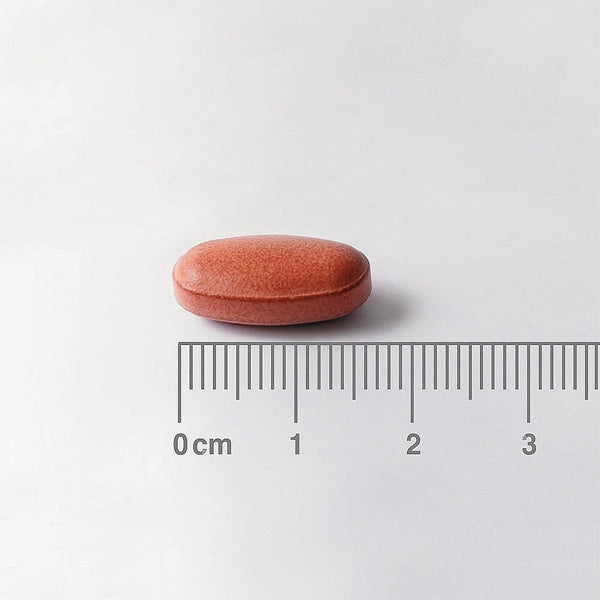 Pink pill with a ruler for scale on a white background