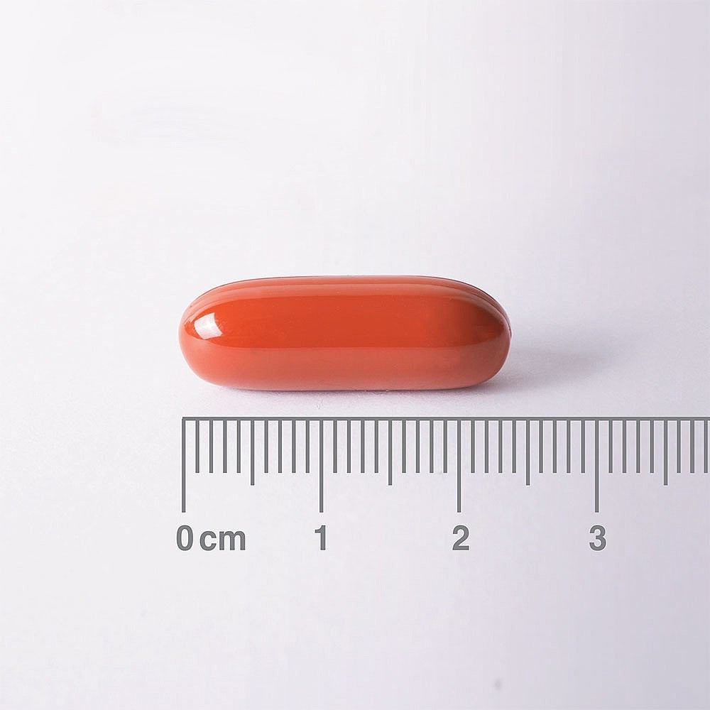 Red pill with a ruler for scale on a white background
