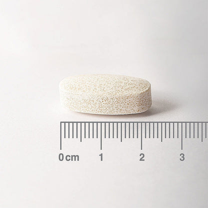 White pill with a ruler for scale on a white background