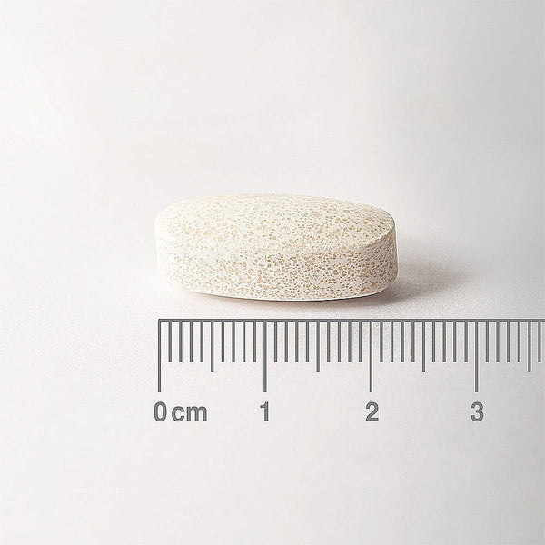 White pill with a ruler for scale on a white background