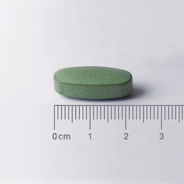 Green pill with a ruler for scale on a white background