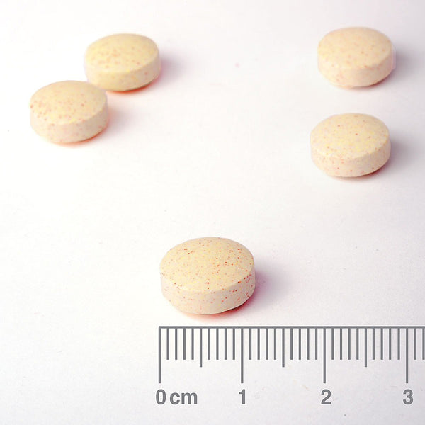 Yellow pills on a white background with a ruler for scale.