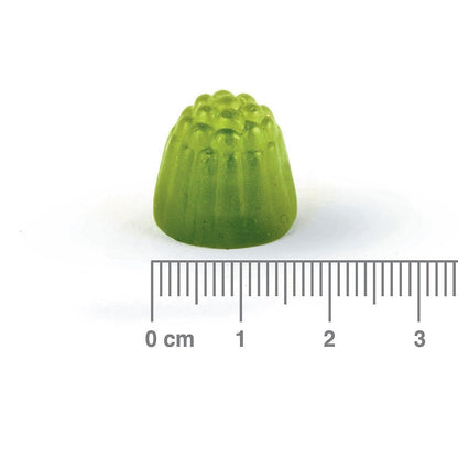 Green gummy with a ruler for scale on a white background