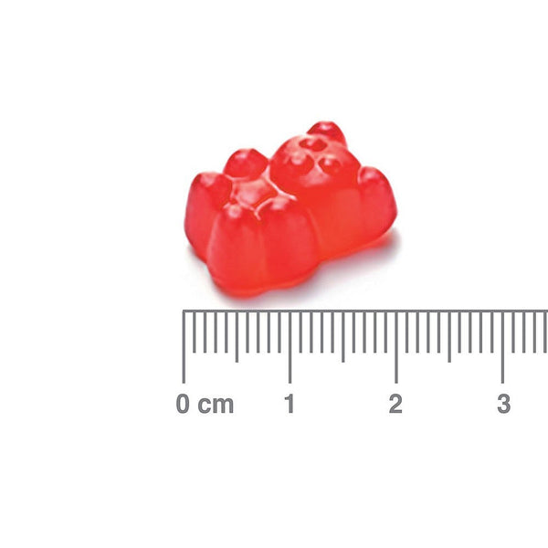 Red gummy bear with a ruler for scale on a white background
