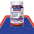 A bottle of Lamberts Multi-Guard for Adults Gummies, featuring a white label with blue and red text, a grape illustration, and a white cap, set against a blue and red graphic background.