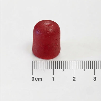 A small red cylindrical cap or plug shown on a white background with a centimeter ruler below it for scale.