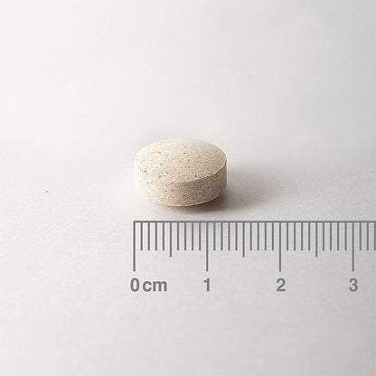 White pill on a light gray background with a ruler for scale.