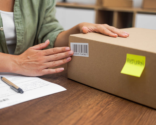 Person with a cardboard box labeled 'RETURN' on a table.