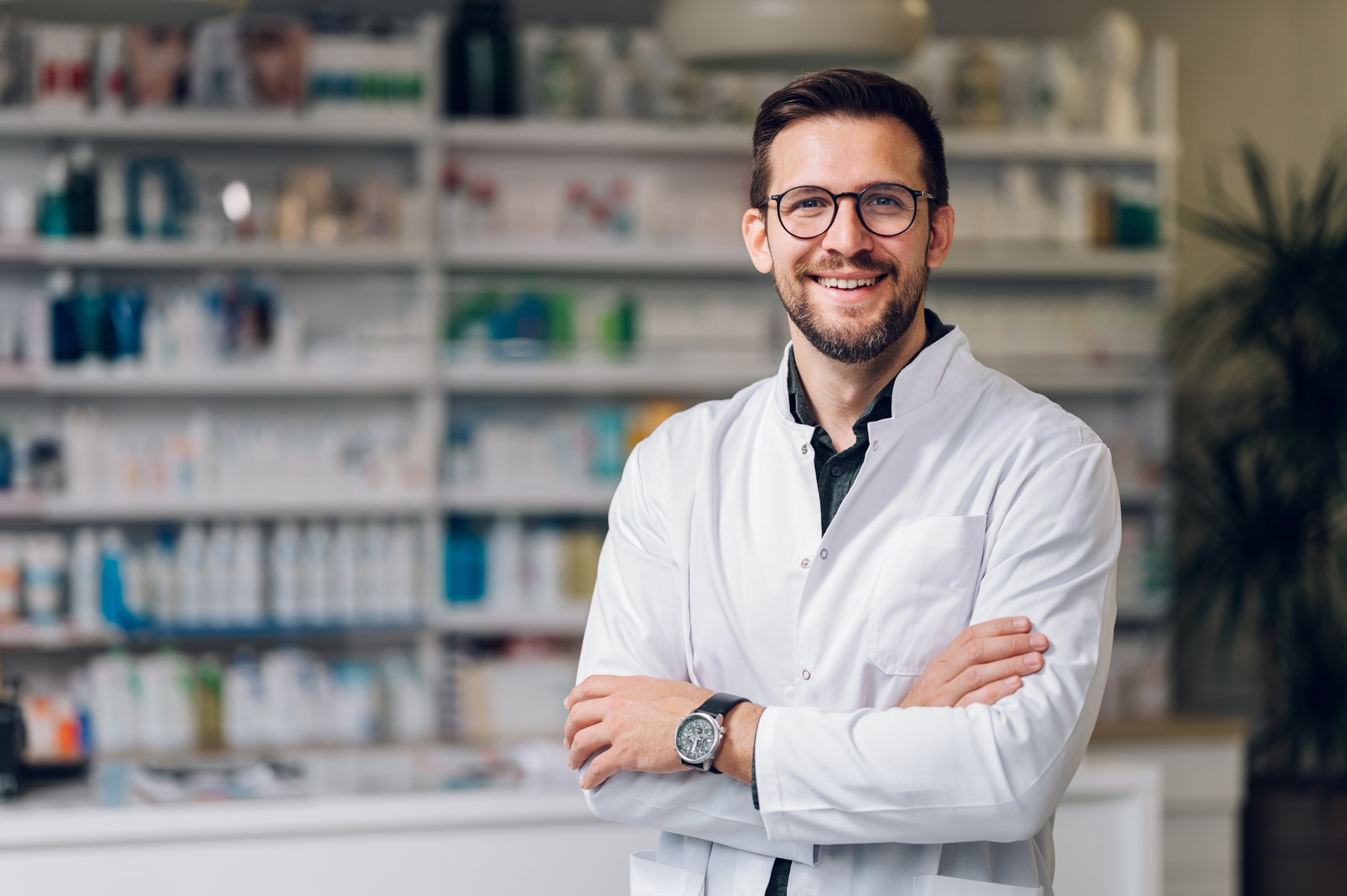 Pharmacist standing in a pharmacy with shelves of medications in the background