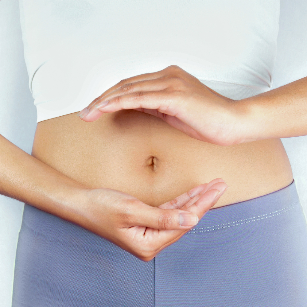 Person touching their stomach with both hands on a plain background