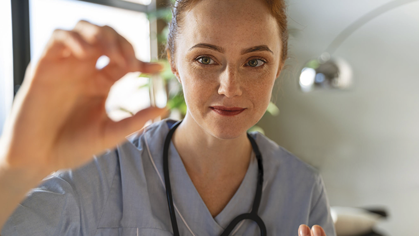 Person in medical scrubs holding a small object with a blurred background