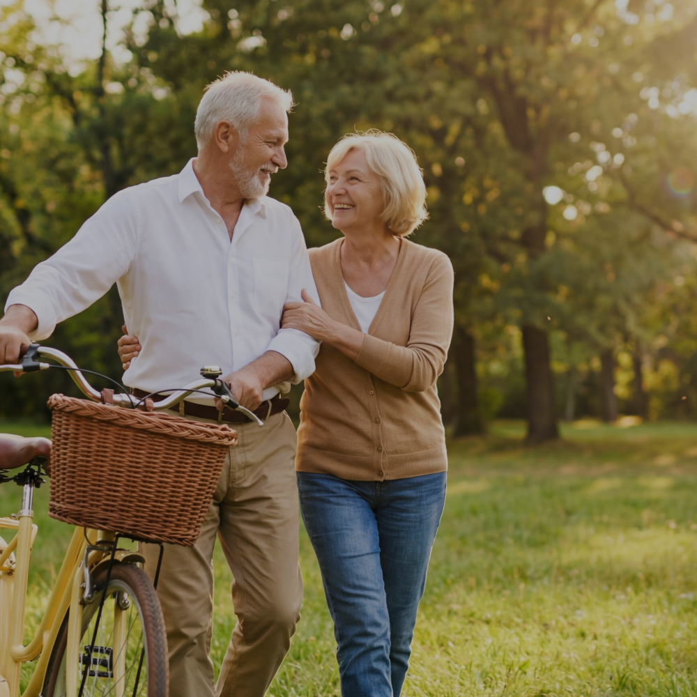 Senior couple walking with a bicycle in a park