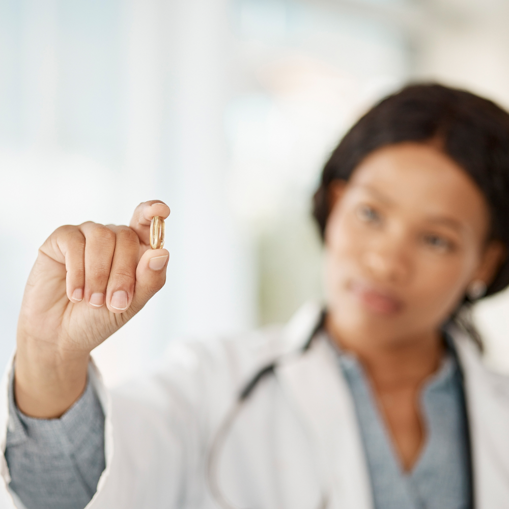 Scientific lady holding fish oil capsule between her fingers
