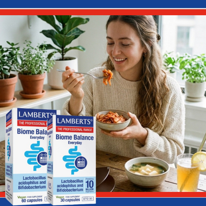 Woman eating a bowl of food with LAMBERTS Biome Balance Everyday supplement boxes in the foreground.