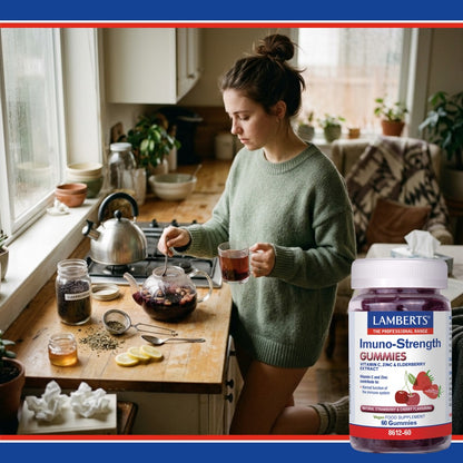 Woman in a kitchen holding a glass of tea with a bottle of Lamberts Imuno-Strength Gummies.