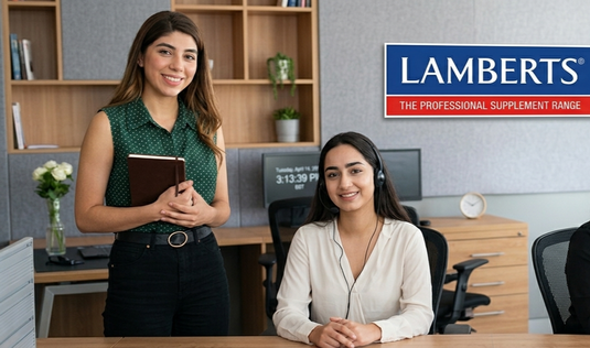 Two women in an office setting with a Lamberts logo in the background